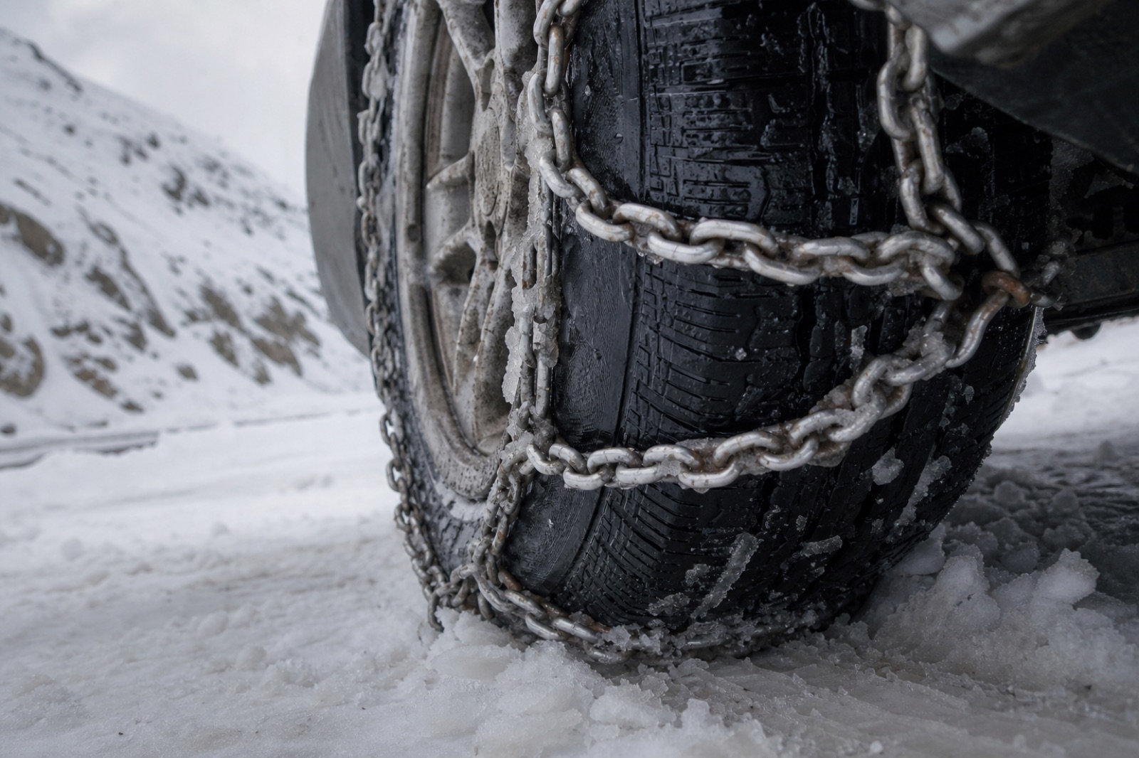Pneu com correntes na neve da estrada da montanha